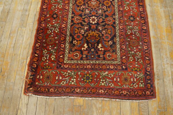 Traditional floral rug in red, navy, and cream on worn wood plank flooring.