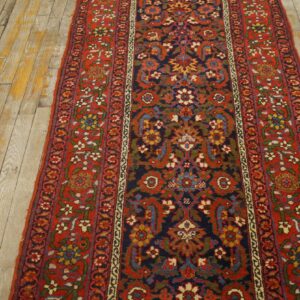 Red and navy traditional runner featuring dense floral patterns on worn light wooden floors.