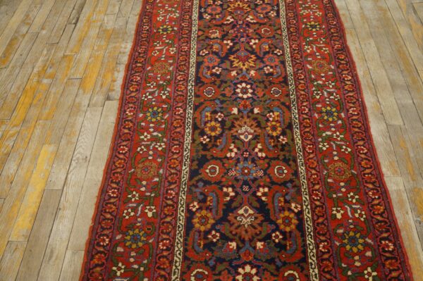 Red and navy traditional runner featuring dense floral patterns on worn light wooden floors.