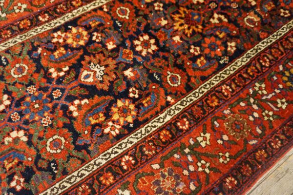 Intricate traditional rug pattern featuring rich red, navy, and colorful floral and geometric details.
