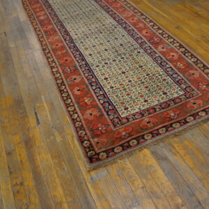 Low-pile runner with rust-red floral borders and a detailed cream field on distressed wood planks.