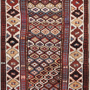 Low-pile runner rug displaying dense geometric tribal patterns in red, dark brown, blue, and cream.