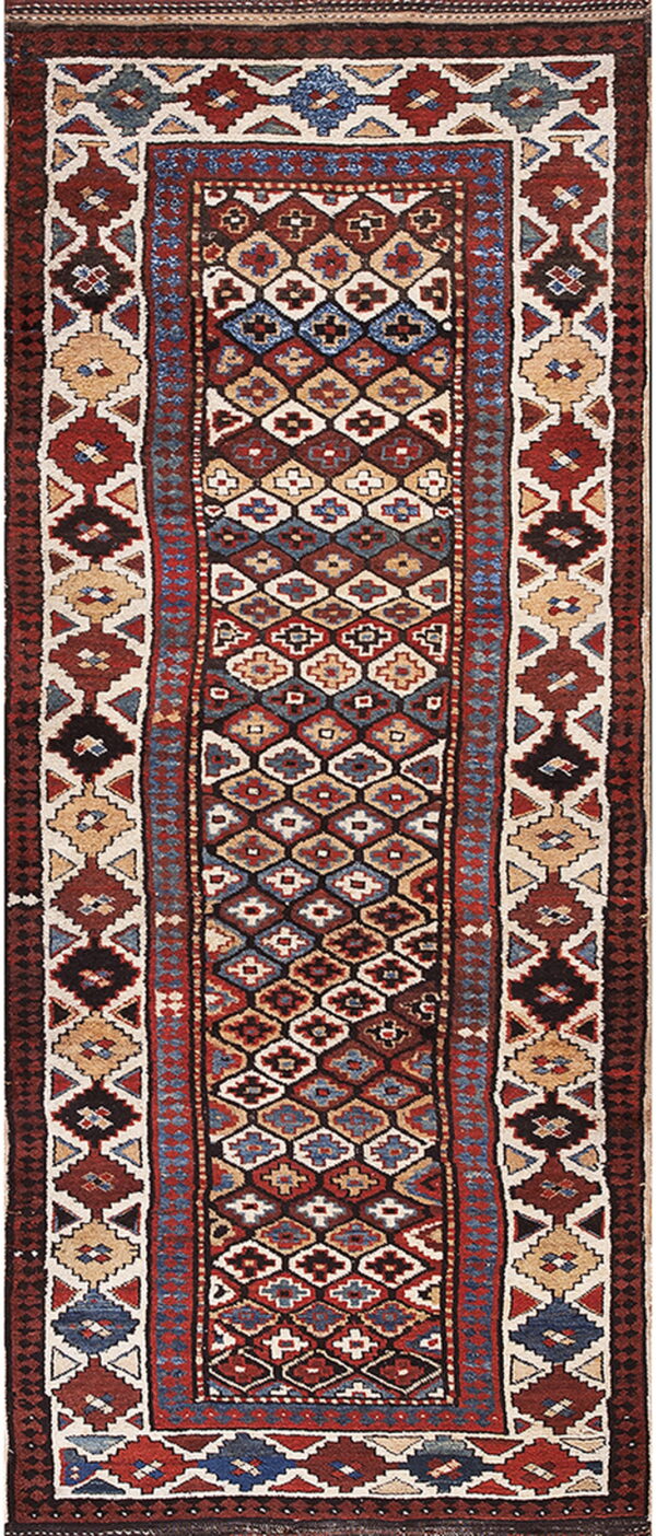 Low-pile runner rug displaying dense geometric tribal patterns in red, dark brown, blue, and cream.