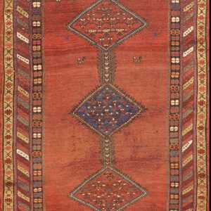 Red runner rug featuring blue and rust diamond medallions and complex multicolored geometric borders.