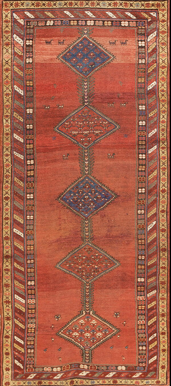 Red runner rug featuring blue and rust diamond medallions and complex multicolored geometric borders.