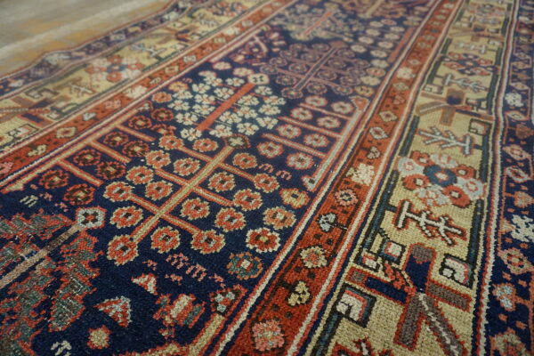 Navy, red, and tan rug showing geometric floral patterns and thick contrasting borders on a floor.