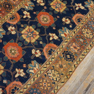 Detailed runner rug featuring geometric and floral patterns in navy, rust, and gold on whitewashed wood flooring.