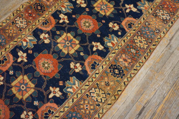 Detailed runner rug featuring geometric and floral patterns in navy, rust, and gold on whitewashed wood flooring.