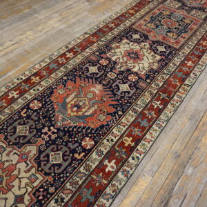 A low-pile runner with navy, red, and cream geometric patterns covers rustic, distressed wood plank flooring.