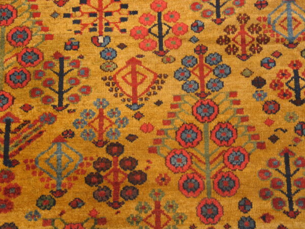 Stylized red, blue, and dark geometric motifs cover a woven mustard gold rug surface.