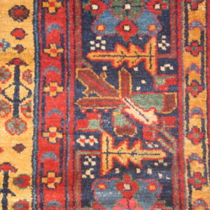 Textured rug detail featuring geometric motifs in deep blue, red, golden yellow, and light green.