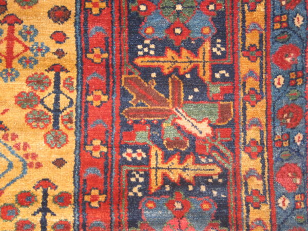 Textured rug detail featuring geometric motifs in deep blue, red, golden yellow, and light green.