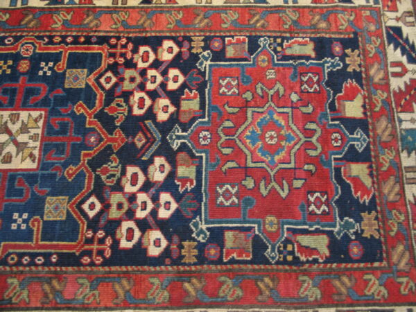 Intricate geometric rug pattern with a navy field, contrasting red motifs, and detailed borders in blue and cream.