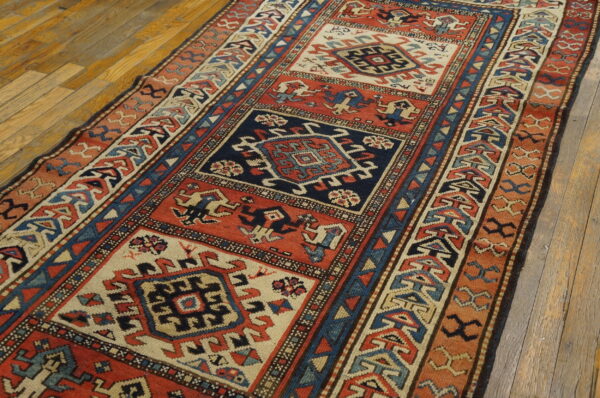 Geometric runner in navy, rust, and cream with repeating square medallions rests on aged hardwood flooring.
