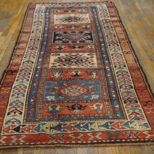Red, navy, and cream geometric runner rug with medallion panels on a wide-plank wood floor.