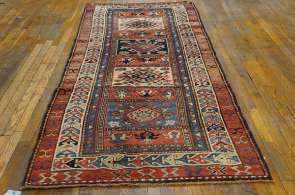 Red, navy, and cream geometric runner rug with medallion panels on a wide-plank wood floor.