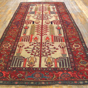 Traditional red and beige runner rug featuring stylized tree motifs and geometric borders on light hardwood flooring.