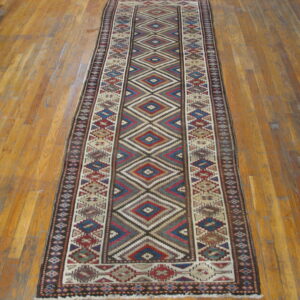 Multicolor geometric runner featuring red, blue, tan, and brown diamonds on a warm wood floor.