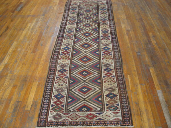 Multicolor geometric runner featuring red, blue, tan, and brown diamonds on a warm wood floor.