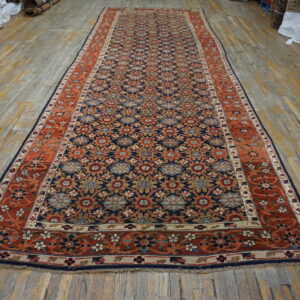 Navy blue runner rug featuring an all-over floral design and rust-colored borders on wood flooring.