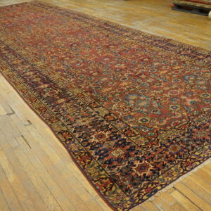 Long runner rug featuring complex red, blue, gold, and navy patterns on distressed wood flooring.