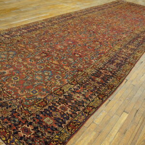 Long runner rug with a dense red, blue, and gold traditional pattern displayed on rustic wood floors.