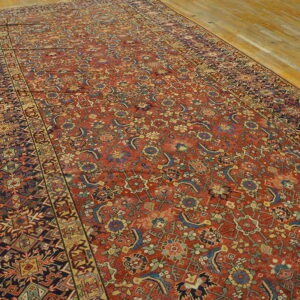 Distressed, low-pile gallery rug with complex red, blue, and gold traditional patterns on wood flooring.