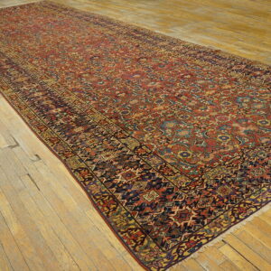 Angled view of a lengthy red and multi-color traditional runner rug on narrow plank wood flooring.
