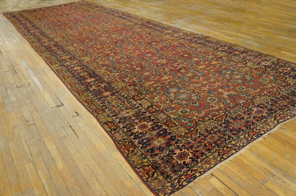 Angled view of a lengthy red and multi-color traditional runner rug on narrow plank wood flooring.