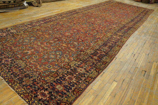 Red runner rug with intricate blue and gold traditional motifs rests on light wood plank flooring.
