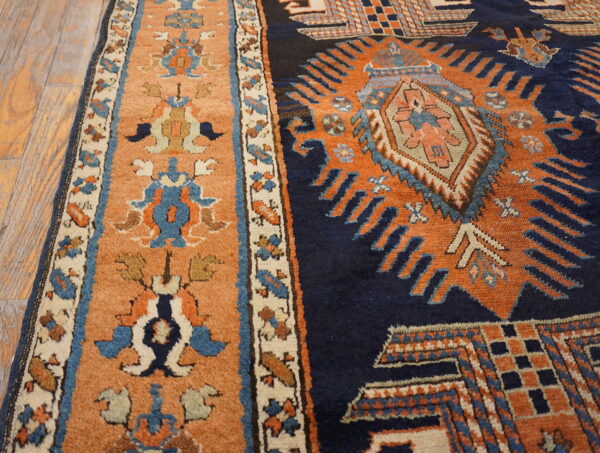 Navy and orange high-pile geometric rug detail resting on rustic light wood flooring.