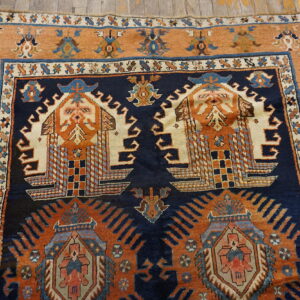 High-pile rug featuring complex geometric motifs in navy, rust, and cream on rustic wooden flooring.