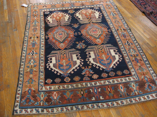Geometric navy blue and terracotta rug with complex tribal designs displayed on a light wood floor.