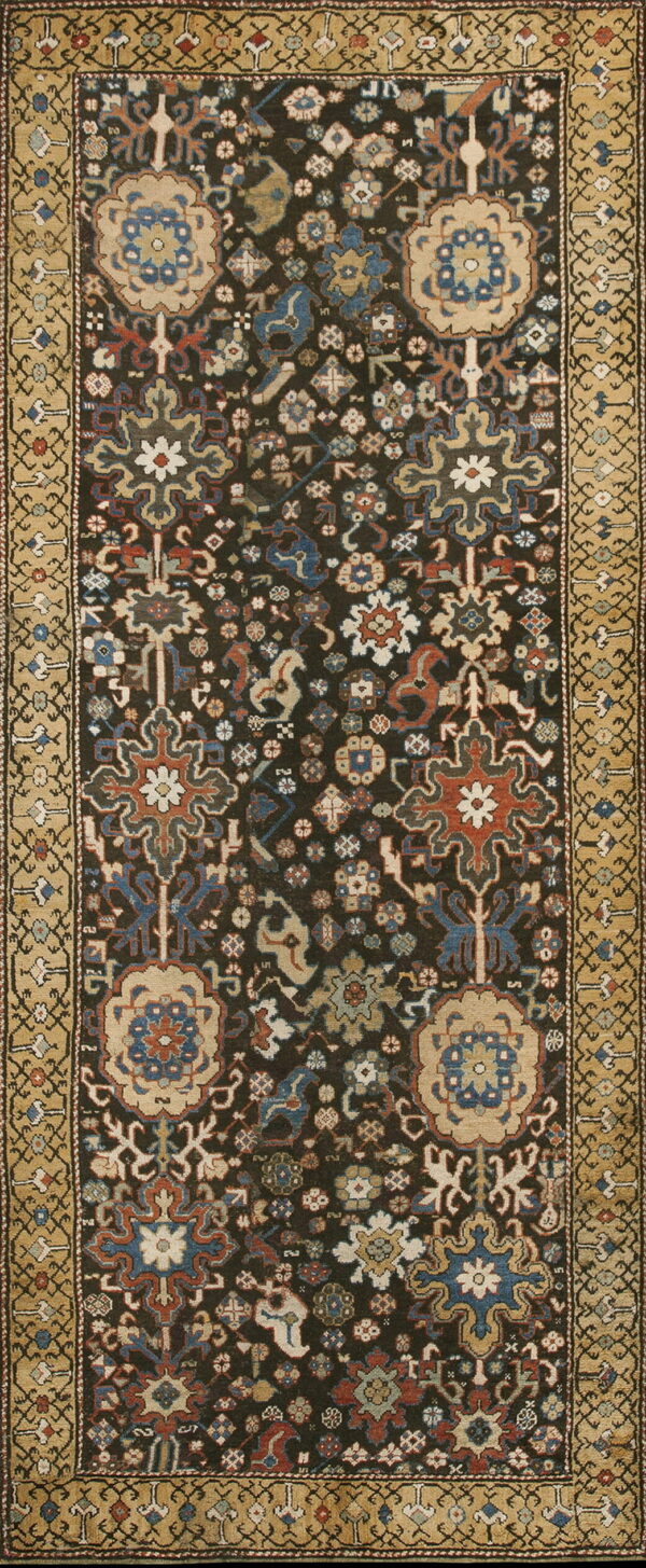 Intricate dark rug featuring colorful stylized medallions and a wide, contrasting gold and tan border.