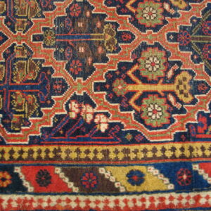 Geometric tribal rug featuring interlocking motifs in navy, red, gold, brown, and green borders.