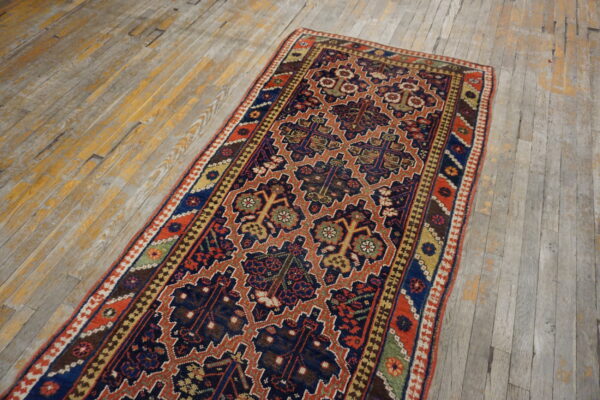 A traditional runner rug with navy, rust, and gold colors lays on distressed, gray-washed wood floors.