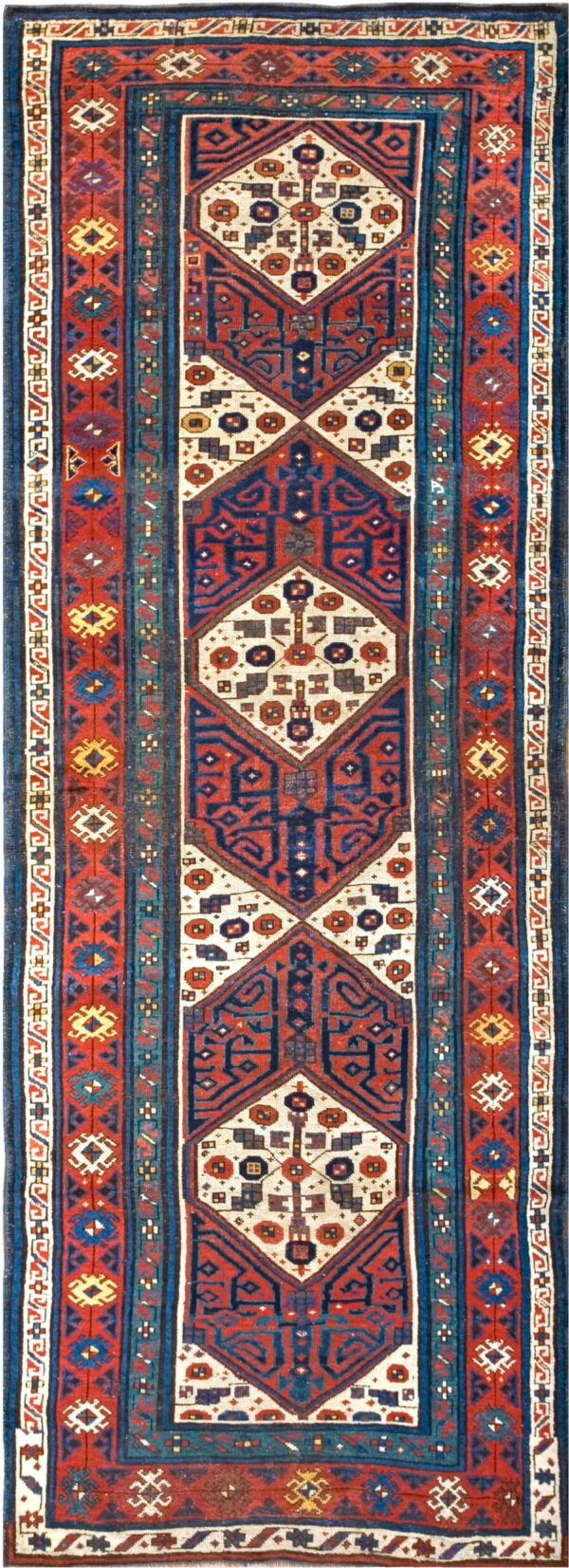 A runner rug with large geometric medallions in navy blue, rust red, and cream colors.