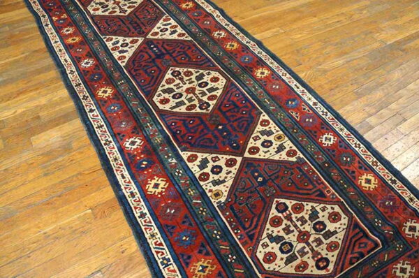 Red, navy, and cream geometric runner rug displayed on light brown wood flooring.