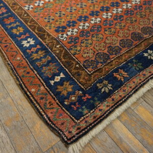 Low pile rug featuring an orange field with geometric motifs and a multi-banded blue and rust border.