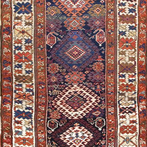 Narrow runner rug featuring repeating tribal geometric patterns in navy blue, rust, cream, and brown.