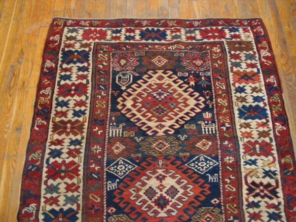 Geometric rug with a navy, red, and cream tribal pattern border resting on natural wood planks.