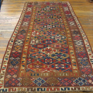 Earthy red and blue geometric runner rug displayed on wide, distressed wooden floor planks.