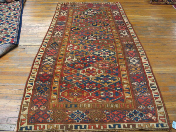 Earthy red and blue geometric runner rug displayed on wide, distressed wooden floor planks.