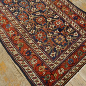 Red and navy traditional rug featuring a dense floral pattern and beige accents on light distressed wood.