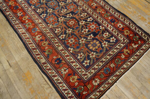 Red and navy traditional rug featuring a dense floral pattern and beige accents on light distressed wood.