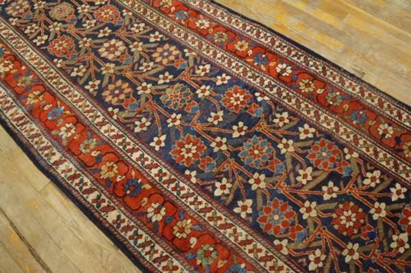 Long runner featuring a complex floral pattern on a navy field and multiple rust red borders over wood floor.