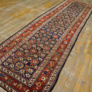 Long navy and rust runner rug with an all-over floral pattern resting on light wood flooring.