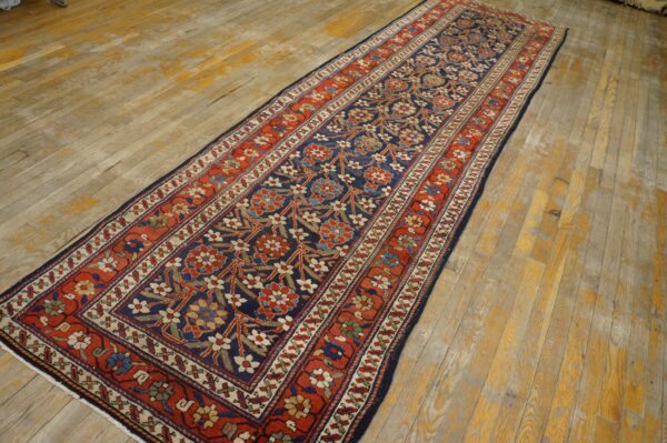 Long navy and rust runner rug with an all-over floral pattern resting on light wood flooring.