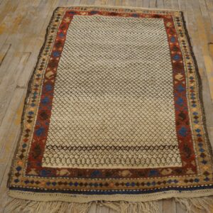 High-pile cream and brown patterned rug with geometric borders rests on distressed wood flooring.