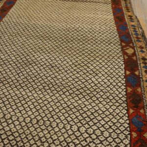 Textured runner featuring small cream and dark brown diamond motifs and colorful borders on light wood flooring.